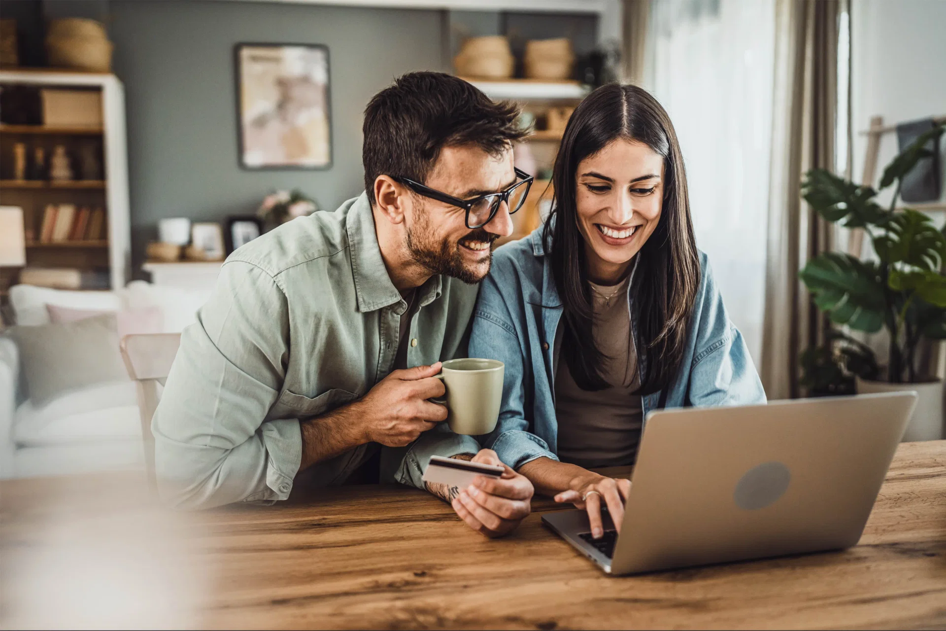 Mercado de Crédito - foto de um casal em sua casa, olhando para a tela do computador e sorrindo