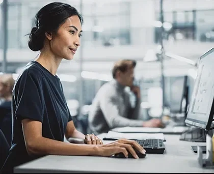 Modelos de concessão de crédito - foto de uma mulher em um ambiente corporativo, ela está sentada, mexendo no computador a sua frente. 
