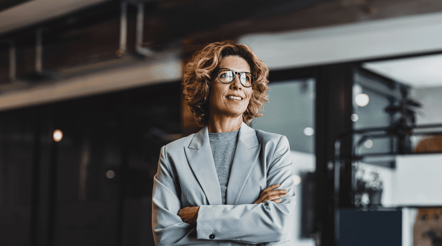 RegTech - foto de uma mulher em ambiente corporativo, de braços cruzados e sorrindo